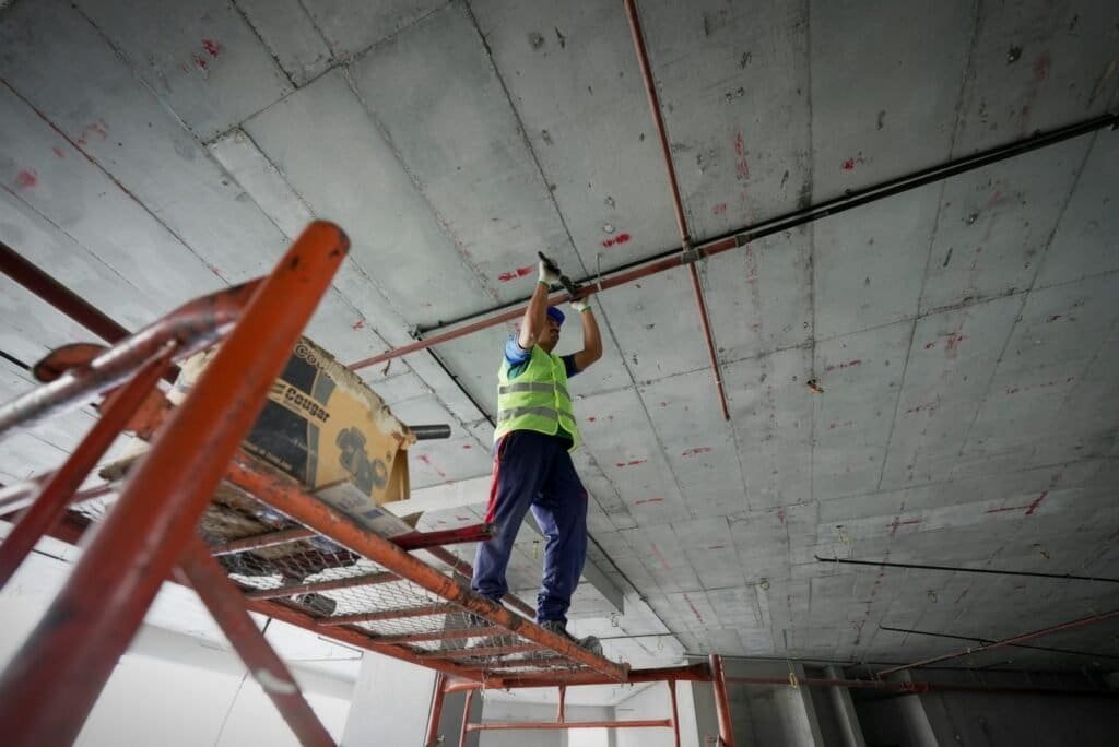 a man standing on a ladder working on a ceiling